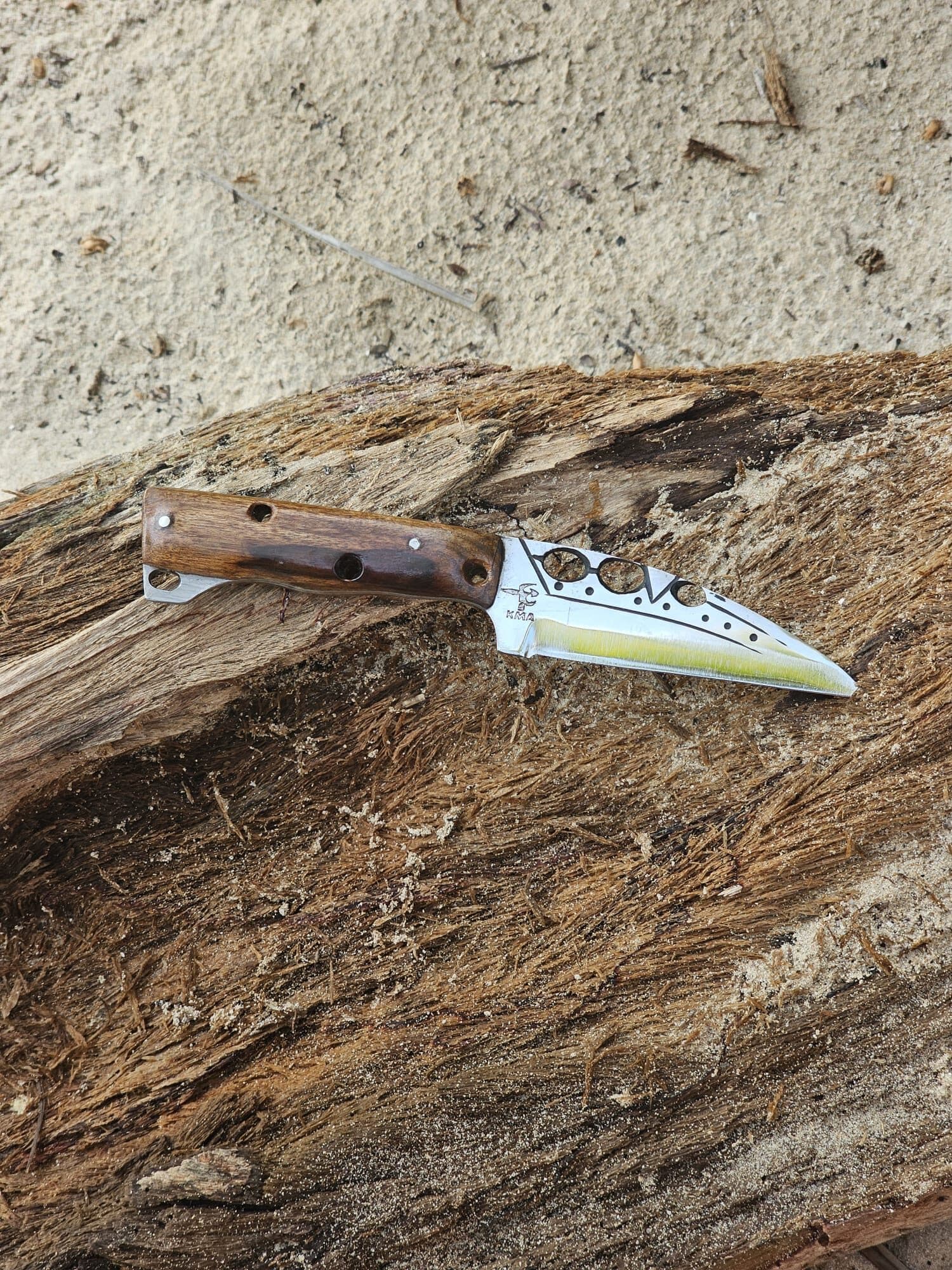 Couteau pliant au manche en bois, posé sur une écorce